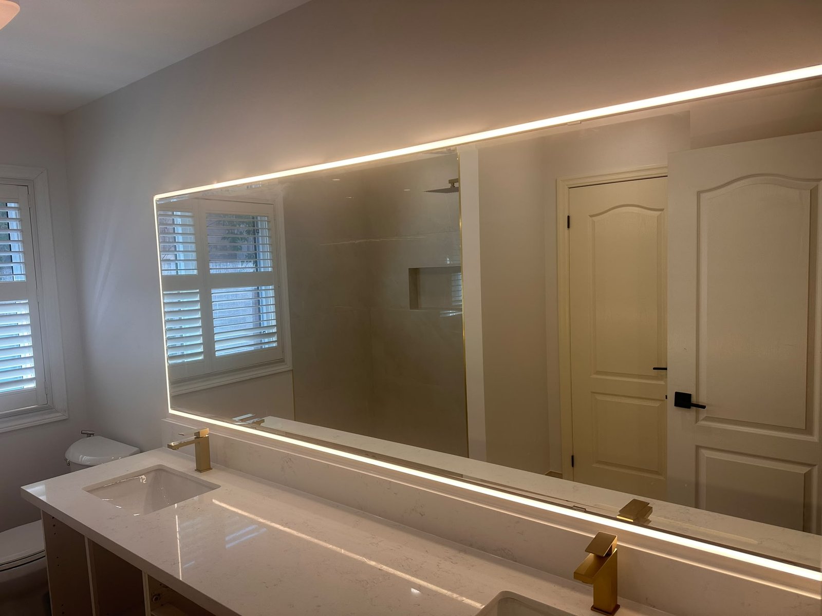Renogate bathroom vanity with backlit mirrors and gold faucets